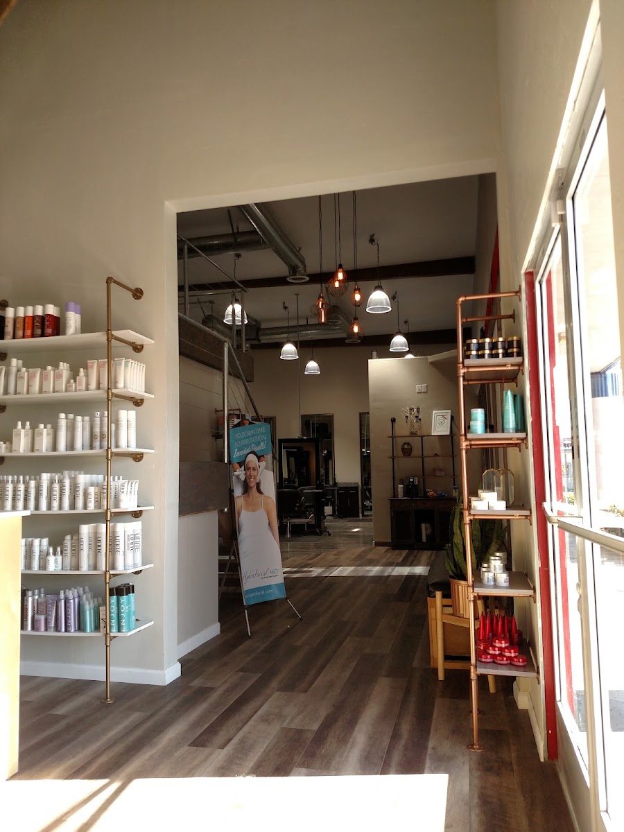 The bright salon entrance with shelves of hair care products leading to the styling floor